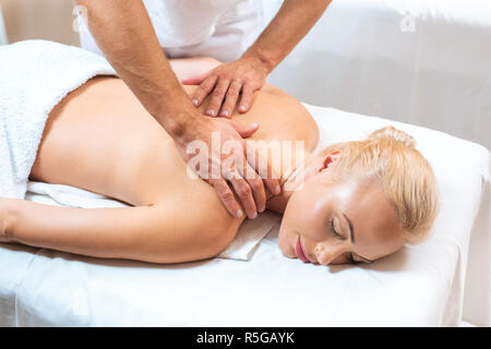 Massaggiatore maschile facendo massaggi per donna bionda Foto Stock