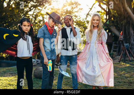 Un gruppo di ragazzi che stanno in giardino nel cortile indossando costumi diversi. Ragazzi e ragazze divertimento all'aperto con costumi di supereroi. Foto Stock