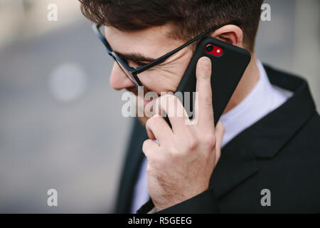 Ravvicinata di un imprenditore sorridente parlando sullo smartphone. Felice maschio professionale business facendo una telefonata. Foto Stock