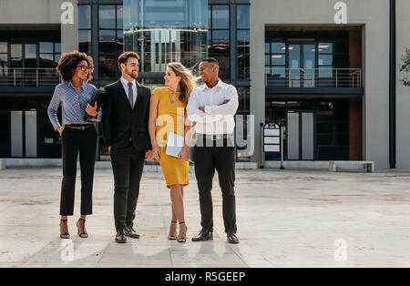 Happy team di business persone in piedi insieme e sorridente. Multi-etnico colleghi di lavoro nella parte anteriore dell'edificio degli uffici. Foto Stock