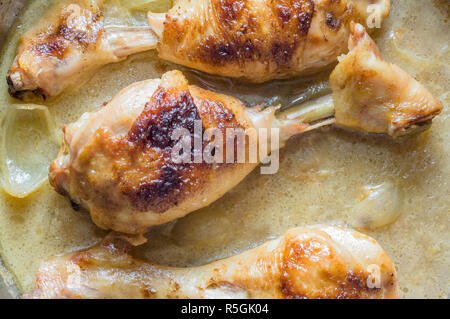 Fried le cosce di pollo in una salsa cremosa con cipolle Foto Stock