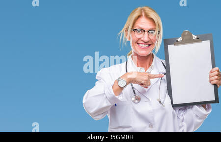 La mezza età bionda medico donna azienda appunti su sfondo isolato molto felice puntando con mani e dita Foto Stock