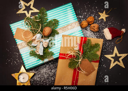 Colorate e decorate regali di Natale su sfondo nero con neve, dadi e golden Stelle di Natale Foto Stock