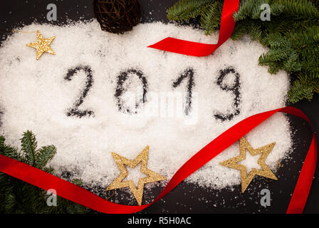2019 scritto nella neve su sfondo nero decorato con rami verdi e Golden Stars Foto Stock