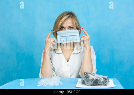 Una donna lab lavoratore mette su una faccia imbottita respiratore con una benda di garza. Foto Stock