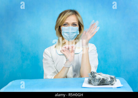 Una donna lab lavoratore mette sulle sue mani di gomma guanti protettivi. Foto Stock