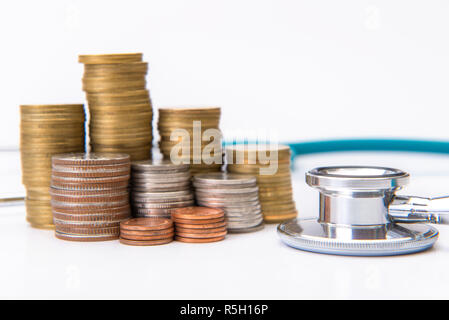 Pila di monete per far crescere il business con strumenti medicali stetoscopio, risparmiando denaro concept Foto Stock