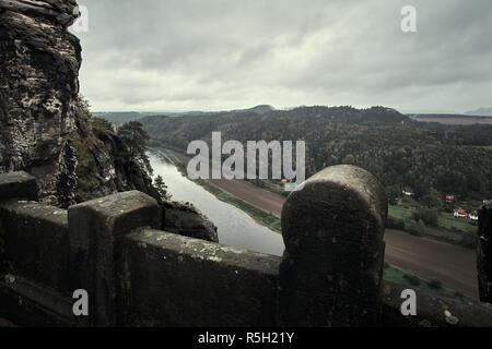 Deadpan dark Ponte Pietra Bastei nella Svizzera sassone con la nebbia di pioggia sul fiume Elba, parco nazionale Svizzera sassone. Foto Stock