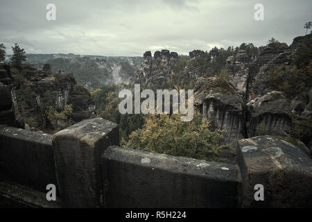 Deadpan dark Ponte Pietra Bastei nella Svizzera sassone con la nebbia di pioggia sul fiume Elba, parco nazionale Svizzera sassone. Foto Stock