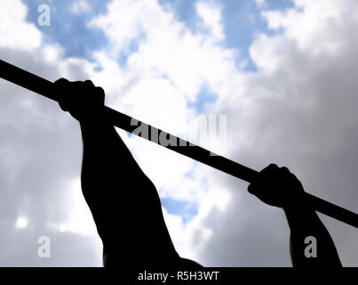 Silhouette di mani su una barra orizzontale. Le mani sulla barra di close-up. L'uomo tira se stesso sulla barra. Sport all'aria fresca. La barra orizzontale. Foto Stock