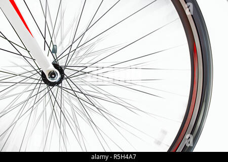 La ruota anteriore della bicicletta ruota rapidamente su uno sfondo bianco. Dettaglio della bici mentre ruota. Foto Stock