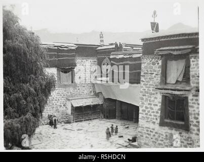 Ingresso Tsuk La Kang, Lhasa. Vista guardando verso il gateway. Il Tsuklakhang è il complesso di edifici del centro di Lhasa che incorpora il Jokhang: " il centro sinistra sul primo piano è la finestra dalla quale abbiamo visto le cerimonie e feste che qui hanno avuto luogo di volta in volta. Dietro la cortina di yak appena sopra è la veranda, da cui il Dalai Lama utilizzato per visualizzarli sul secondo piano. A sinistra è il salice piangente noto come 'Buddha capelli.". Fotografie del Tibet e del Sikkim. Raccolta della campana. 1920-21. 438 stampe 125x100mm a 160x115mm di gelatina stampe d'argento, Foto Stock