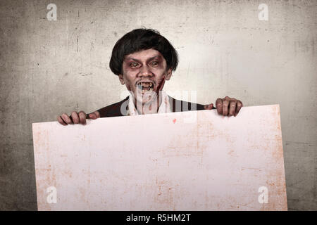Creepy e sanguinosa asian zombie uomo azienda banner vuoto Foto Stock