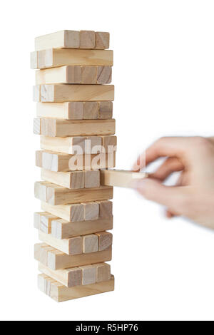 Mano d'uomo prendendo il primo blocco o mettendo ultimo blocco di una robusta torre di blocchi di legno. Concetto foto di pianificazione, tenendo conto dei rischi e la definizione di strategie. Foto Stock