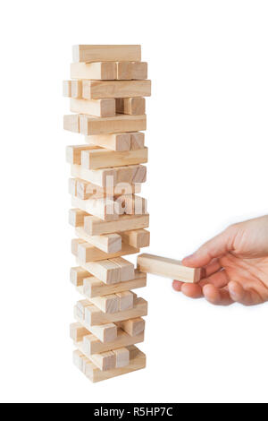 Mano d'uomo prendendo o mettere un blocco a un instabile e torre incompleta dei blocchi di legno. Concetto foto di pianificazione, tenendo conto dei rischi e la definizione di strategie. Foto Stock