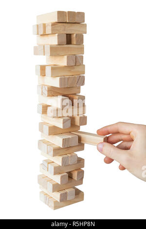 Mano d'uomo prendendo o mettere un blocco a un instabile e torre incompleta dei blocchi di legno. Concetto foto di pianificazione, tenendo conto dei rischi e la definizione di strategie. Foto Stock