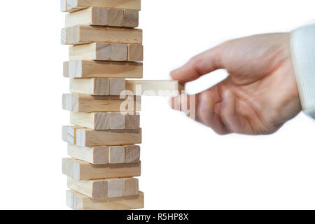 Mano d'uomo prendendo il primo blocco o mettere l'ultimo blocco di una robusta torre di blocchi di legno. Concetto foto di pianificazione, tenendo conto dei rischi e la definizione di strategie. Foto Stock