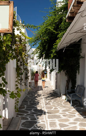 Due turisti femmina passeggiare lungo uno stretto vicolo in isola di Paros, Grecia. Foto Stock