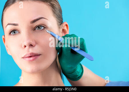 Chirurgo cosmetico esaminando client femmina in ufficio. Controllo medico volto di donna, la palpebra prima di un intervento di chirurgia plastica, della Blefaroplastica. Chirurgo o estetista mani toccano donna faccia Foto Stock