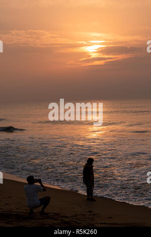 Silhouette di persone a Puri Beach al momento del sorgere del sole. Foto Stock