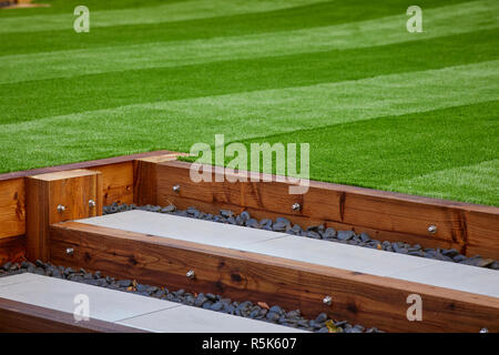 Senza necessità di manutenzione del manto erboso artificiale prato un moderno campo in erba sintetica tappeto con traversina in legno passi Foto Stock