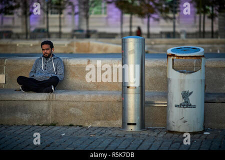 Pier Head Liverpool Waterfront uomo in appoggio sulla sede pubblica l uomo dalla pietra Foto Stock