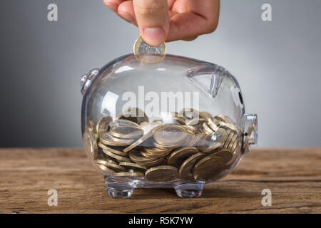 Lato inserimento di moneta in trasparente Salvadanaio Foto Stock