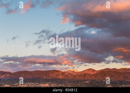 Drammatico, bel tramonto proietta viola e arancione i colori sulle nuvole e le montagne al di sopra di un quartiere di Tesuque, vicino a Santa Fe, New Mexico Foto Stock