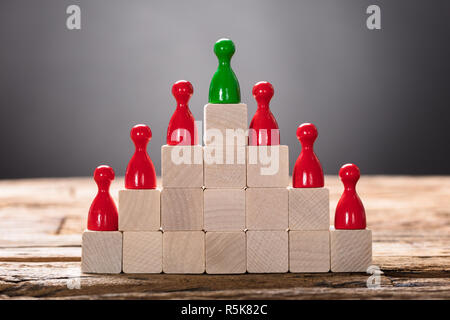 Il verde e il rosso pedina figurine disposte su dei blocchi di legno Foto Stock