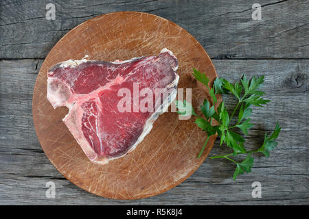 Raw manzo secco t-bone steak con prezzemolo Foto Stock