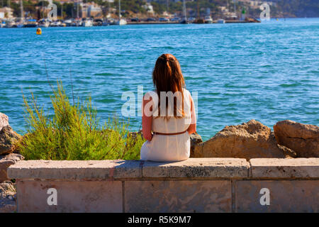 Giovane donna seduta su una parete in porto Foto Stock