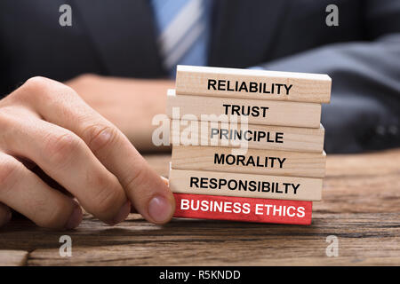 Imprenditore azienda Red Business Ethics blocco sotto torre di legno Foto Stock