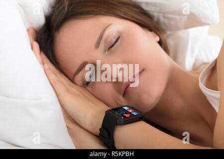 Donna che Dorme con Smart Guarda che mostra la frequenza cardiaca Foto Stock