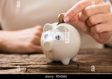 Persona inserimento di moneta in Piggybank Foto Stock