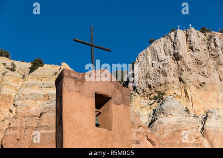 Il campanile e il legno rustico croce della chiesa abbaziale e scogli colorati presso il monastero di Cristo nel deserto vicino a Abiquiu, Nuovo Messico Foto Stock