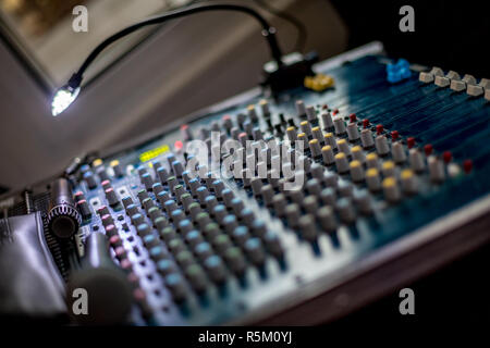 Messa a fuoco selettiva o la profondità di campo di una notte foto del mixer audio con una piccola lampada accesa e il microfono. Sfondo sfocato Foto Stock