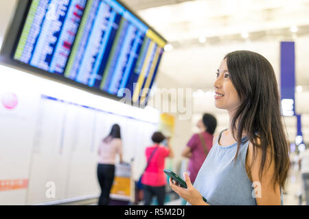 Donna controllando il numero di volo a bordo in aeroporto Foto Stock