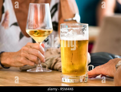 Le mani di un paio di birra e vino bianco seduto in un tavolo all'aperto un bar a spli, Croazia. Foto Stock