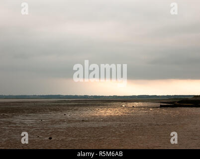 Sunsetting nella distanza incredibile luce sulle velme bagliore di colata bella spiaggia. Foto Stock