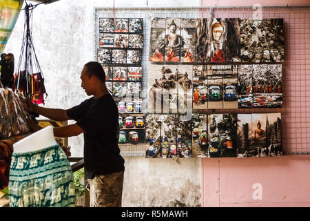 Damnoen Saduak - 4 Marzo 2014: un venditore a vendere arte e altri souvenir regola il suo display. Il mercato galleggiante è molto famoso. Foto Stock