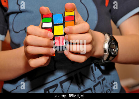 Un ragazzo che gioca con un cubo di Rubik puzzle. Foto Stock