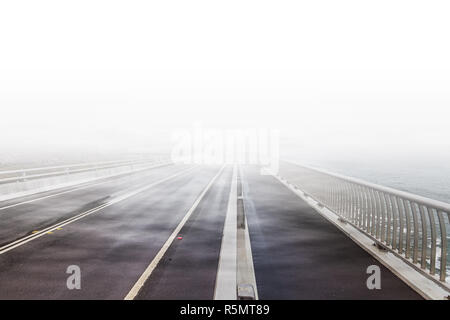 Sea Cliff Bridge Road a scomparire nel bianco delle nuvole e la nebbia Foto Stock