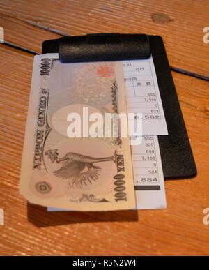Yen giapponese su una piastra di bill in un ristorante di Tokyo con un ricevimento Foto Stock