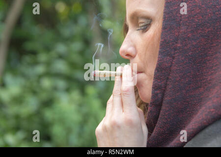 Giovane donna attraente di fumare la cannabis o la marijuana fuori comune. Foto Stock