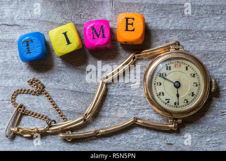 Lettera di tempo cubo e orologio sul legno grigio. visualizzazione Foto Stock