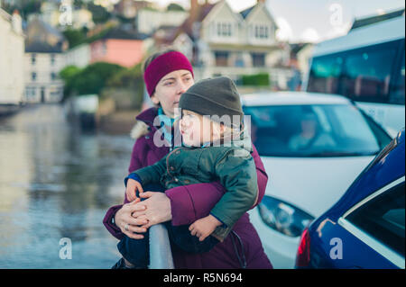 Una giovane donna e un po' di bambino sono di attraversare il fiume in inverno su un traghetto per auto Foto Stock