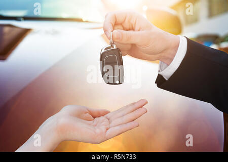 Venditore di consegnare la chiave per donna dalla nuova vettura Foto Stock