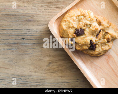 Biscotti al cioccolato e noci di macadamia. Posto su un piatto di legno.Caffè concetto del freno. Foto Stock