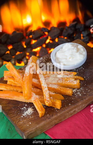 Su un bancone piastrellato nero vengono offerte porzioni di patatine fritte  con sopra formaggio e carne macinata di manzo t