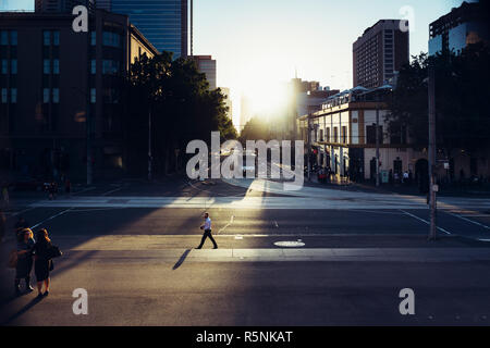 La gente seduta sulle scale di casa del Parlamento la visione di Melbourne henge, quando il sole tramonta in linea con la griglia del CBD di Melbourne, Australia Foto Stock